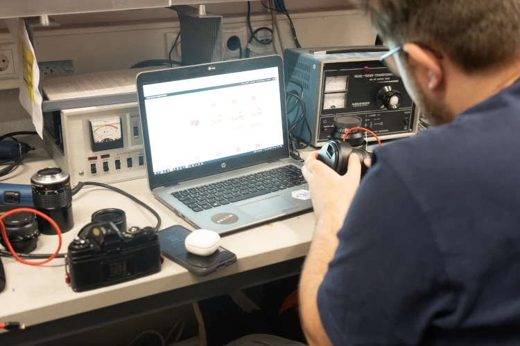 A person working on analog cameras in front of a notebook